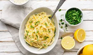 Aksamitne spaghetti z cytryną i parmezanem, ozdobione świeżą natką pietruszki. Idealne pasta al limone.