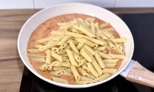 Penne w kremowym sosie pomidorowym z kawałkami chorizo, gotowe do podania.