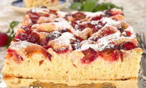 Puszyste ciasto ze śliwkami, posypane cukrem pudrem, wygląda apetycznie. Idealne na letnie popołudnie.