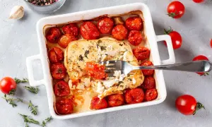Pyszna, pieczona feta z pomidorkami koktajlowymi i ziołami, gotowa do podania.