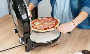 Osoba wkłada pizzę do pieca. Dowiedz się, w jakiej temperaturze piec pizzę, aby uzyskać idealny smak.