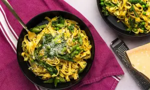 Pyszne pasta primavera z zielonymi warzywami i parmezanem, podane na talerzu.