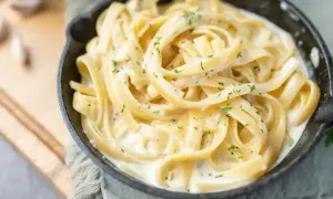 Pyszny makaron fettuccine w kremowym sosie, posypany natką pietruszki. Idealny pomysł, z czym zrobić makaron na szybko.