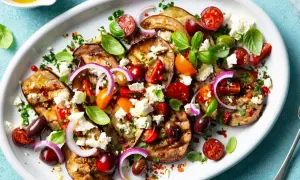 Pyszna sałatka z grillowanych warzyw: bakłażan, pomidorki, oliwki, cebula i ser feta, skropiona oliwą.