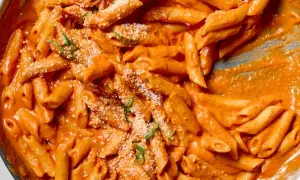 Penne alla vodka w kremowym, pomarańczowym sosie, posypane parmezanem i bazylią. Pyszne danie gotowe do podania.