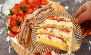 Pyszny tort truskawkowy z bitą śmietaną i świeżymi owocami, kroimy pierwszy kawałek.