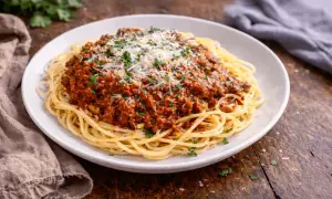 Pyszne makaron spaghetti z bogatym sosem bolońskim, posypane parmezanem i natką pietruszki.