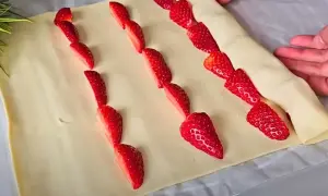 Słodkie truskawki w cieście francuskim układane w rzędach, gotowe do pieczenia.