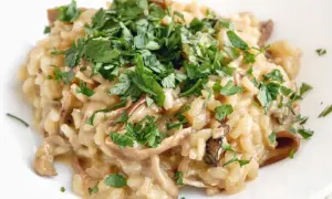 Kremowe risotto z grzybami, posypane świeżą natką pietruszki, wygląda apetycznie.