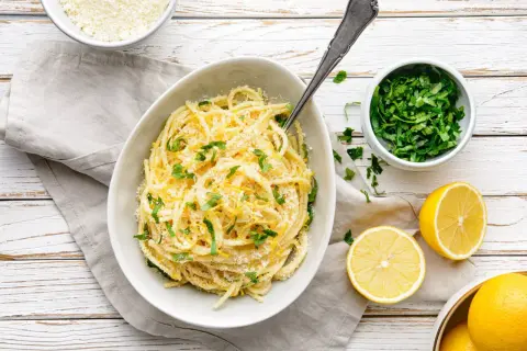 Aksamitne spaghetti z cytryną i parmezanem, ozdobione świeżą natką pietruszki. Idealne pasta al limone.
