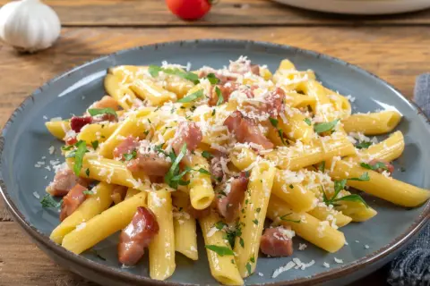 Penne rigate z chrupiącym boczkiem, posypane parmezanem i natką pietruszki. Idealne makaron z boczkiem na szybki obiad.