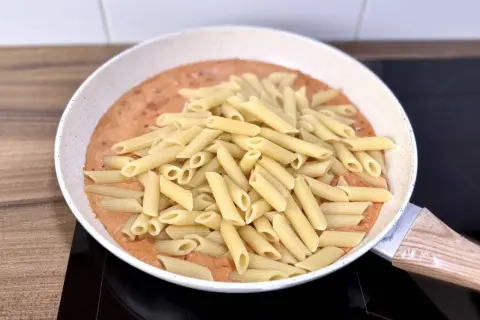 Penne w kremowym sosie pomidorowym z kawałkami chorizo, gotowe do podania.