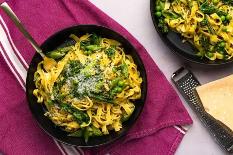 Pyszne pasta primavera z zielonymi warzywami i parmezanem, podane na talerzu.