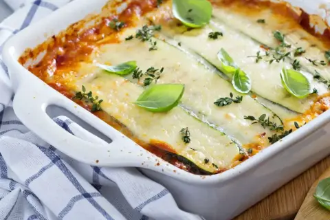 Pyszne lasagne ze szpinakiem i cukinią, zapieczone pod warstwą sera, ozdobione bazylią i tymiankiem.