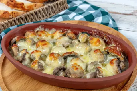 Pyszne pieczarki z piekarnika, zapieczone pod ciągnącym się serem, kuszą apetycznym wyglądem. Idealne na szybką przekąskę.