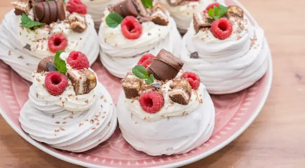 Mini pavlova z bitą śmietaną, malinami i kawałkami czekolady. Idealne na deser.