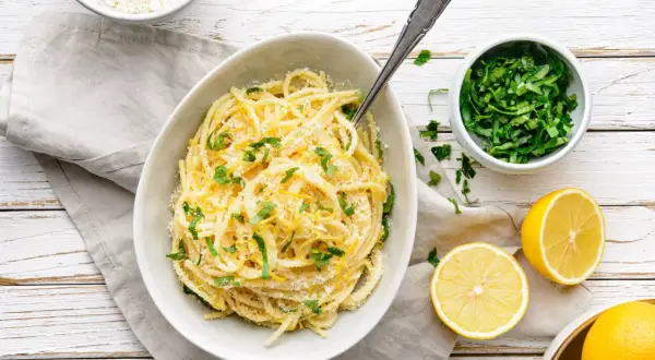 Aksamitne spaghetti z cytryną i parmezanem, ozdobione świeżą natką pietruszki. Idealne pasta al limone.