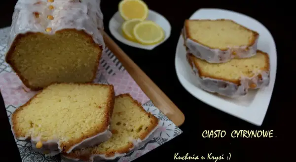 Pyszne ciasto cytrynowe z lukrem, pokrojone na kawałki, obok plasterki cytryny.