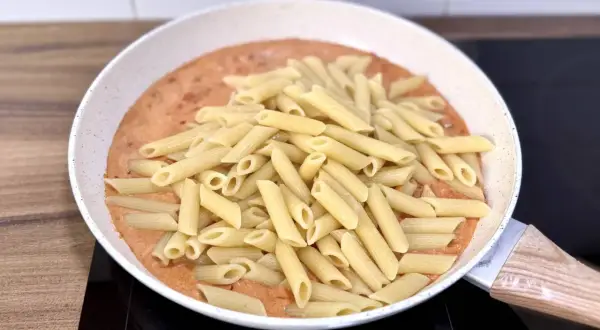 Penne w kremowym sosie pomidorowym z kawałkami chorizo, gotowe do podania.
