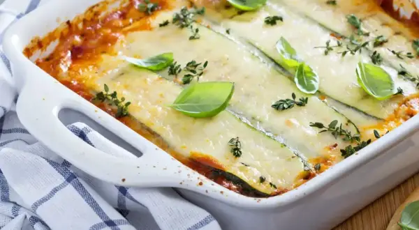 Pyszne lasagne ze szpinakiem i cukinią, zapieczone pod warstwą sera, ozdobione bazylią i tymiankiem.