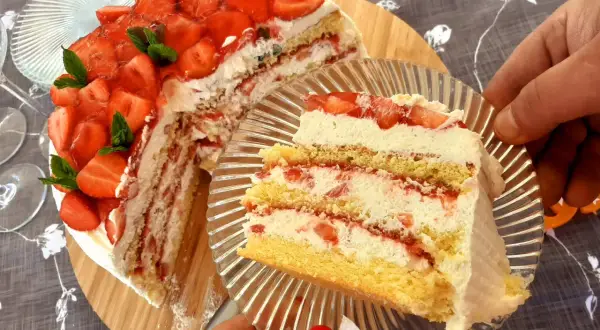 Pyszny tort truskawkowy z bitą śmietaną i świeżymi owocami, kroimy pierwszy kawałek.