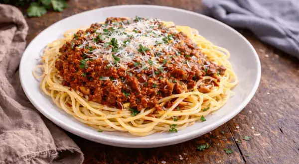 Pyszne makaron spaghetti z bogatym sosem bolońskim, posypane parmezanem i natką pietruszki.