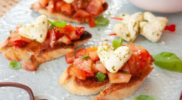 Pyszna bruschetta przepis: chrupiące grzanki z pomidorami, bazylią i mozzarellą w kształcie serc. Idealna na romantyczną kolację.