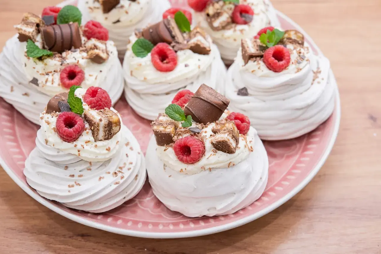 Mini pavlova z bitą śmietaną, malinami i kawałkami czekolady. Idealne na deser.