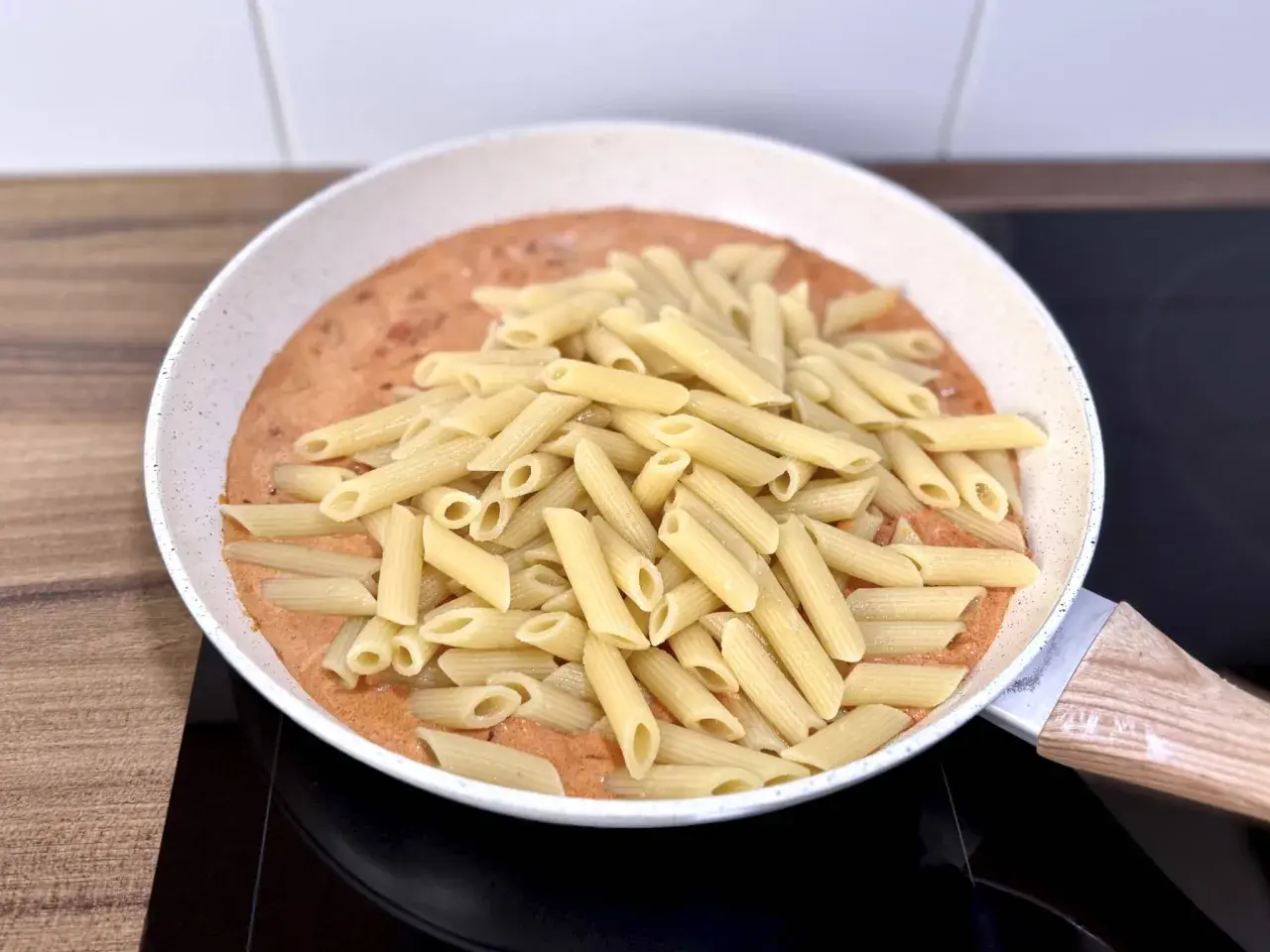 Penne w kremowym sosie pomidorowym z kawałkami chorizo, gotowe do podania.