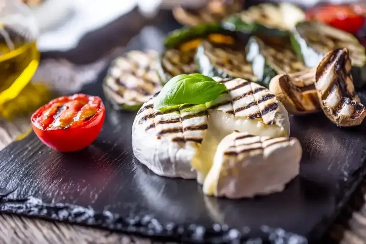 Pyszny camembert z grilla, z rumianymi paskami, podany z grillowanymi warzywami i pomidorkiem. Idealna przekąska na lato.