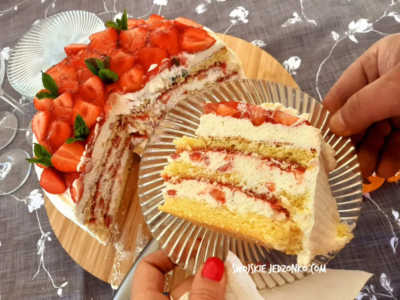 Pyszny tort truskawkowy z bitą śmietaną i świeżymi owocami, kroimy pierwszy kawałek.