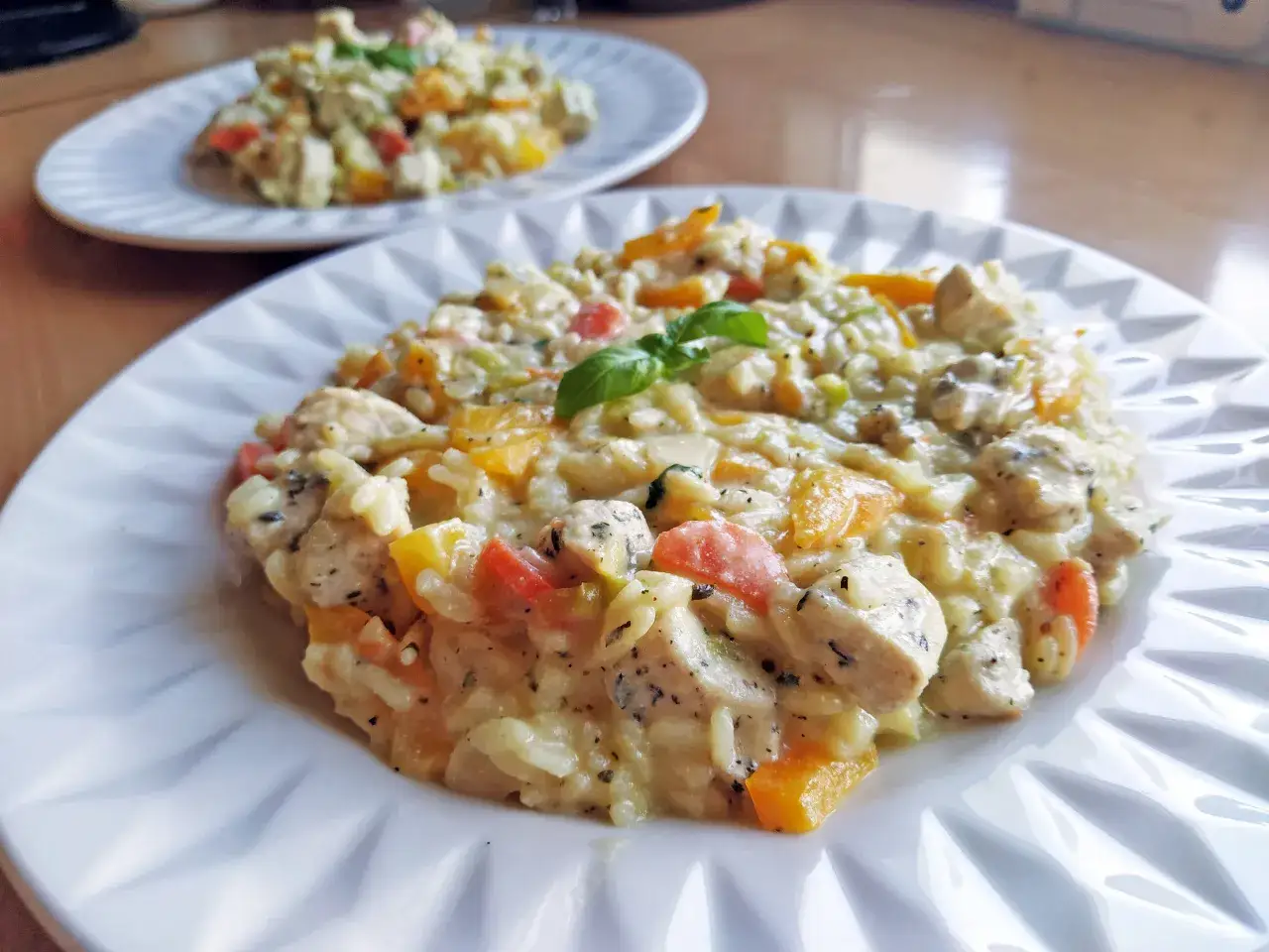 Pyszne risotto z kurczakiem, papryką i bazylią na białym talerzu. Idealne na obiad.