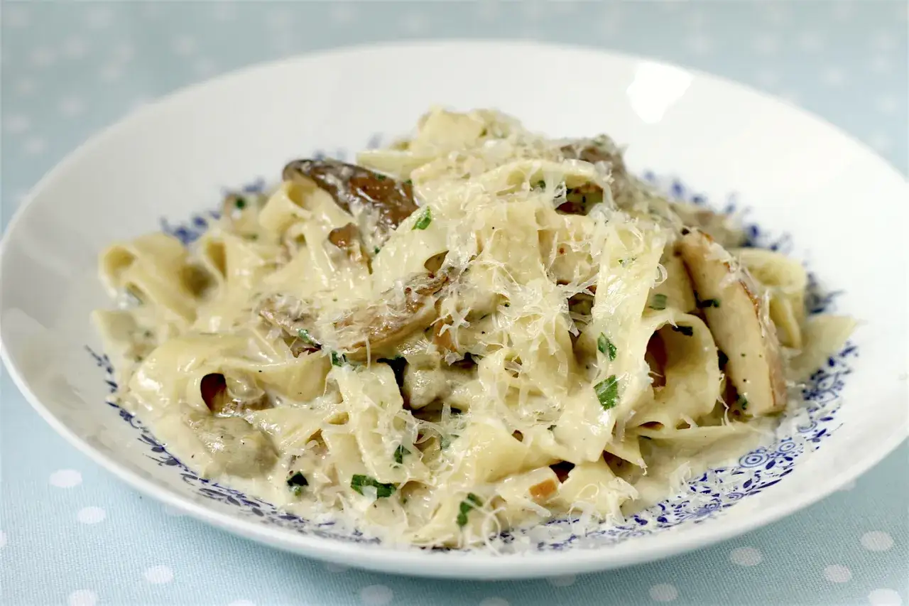 Pyszny makaron z borowikami w kremowym sosie, posypany parmezanem i natką pietruszki.