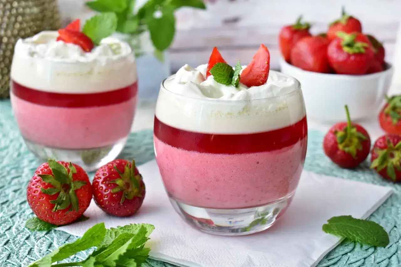 Pyszny deser z warstwami musu i galaretki, ozdobiony bitą śmietaną i truskawkami. Idealny sorbet truskawkowy na letnie popołudnie.