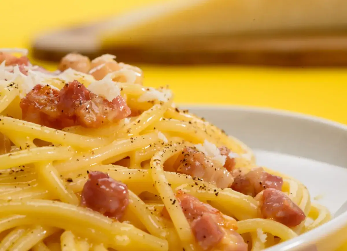 Pyszne spaghetti carbonara z kawałkami guanciale i startym parmezanem. Idealny wyb&oacute;r, jeśli zastanawiasz się, jaki ser do carbonary.