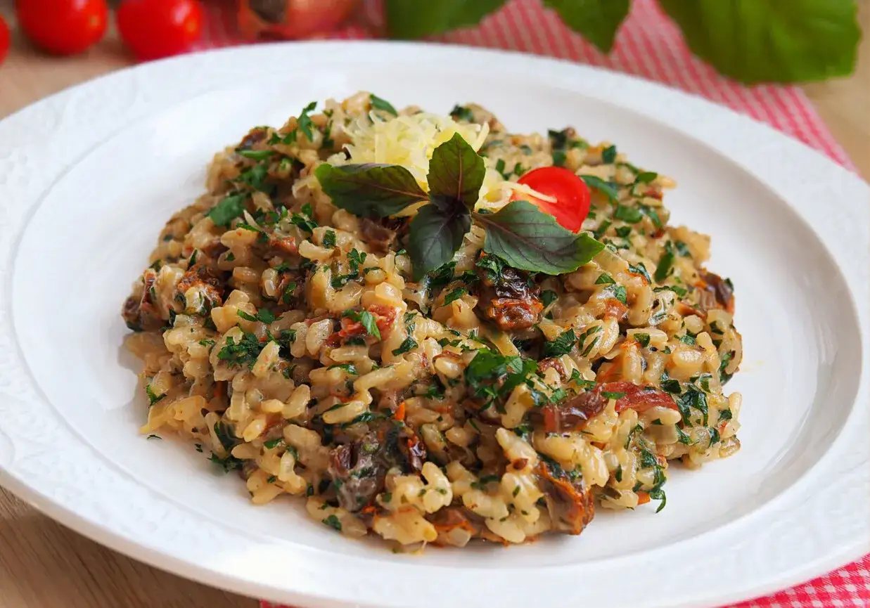 Pyszne risotto pomidorowe z suszonymi pomidorami i bazylią, posypane parmezanem. Idealne na letni obiad.