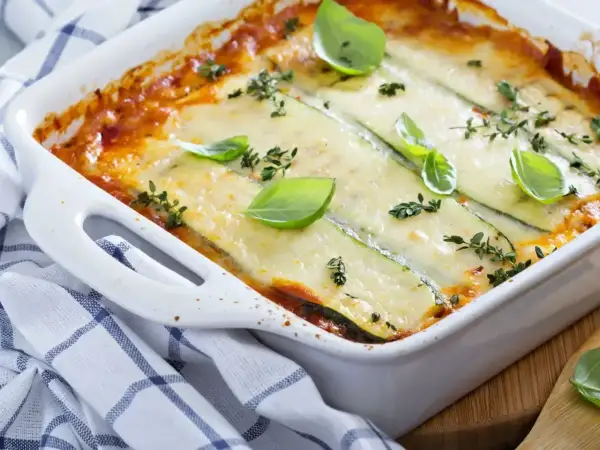 Pyszne lasagne ze szpinakiem i cukinią, zapieczone pod warstwą sera, ozdobione bazylią i tymiankiem.