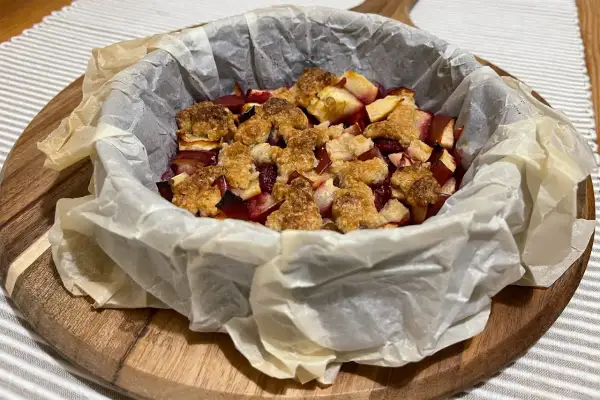 Pyszne owoce pod kruszonką, zapieczone w papierze do pieczenia, gotowe do podania.