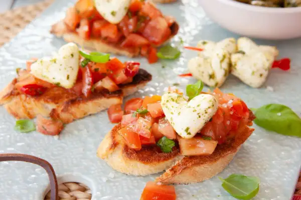 Pyszna bruschetta przepis: chrupiące grzanki z pomidorami, bazylią i mozzarellą w kształcie serc. Idealna na romantyczną kolację.
