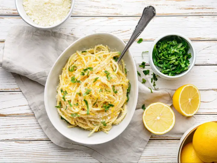 Aksamitne spaghetti z cytryną i parmezanem, ozdobione świeżą natką pietruszki. Idealne pasta al limone.